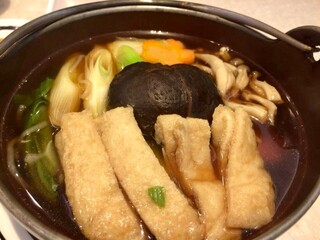 a serve of iron hot pot Vegetarian udon with chives, tofu, shiitake mushrooms, and carrots on the table