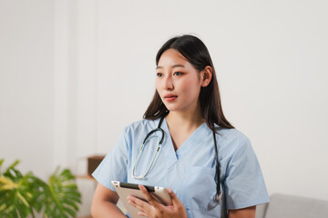Female Healthcare Professional in Scrubs Holding Tablet and Listening in Medical Environment with Stethoscope