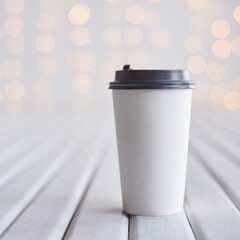 Minimalist white coffee cup on wooden surface with soft bokeh light background for simple and elegant design.