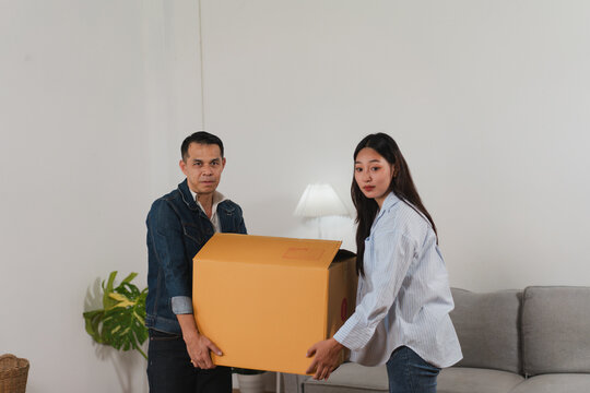Young Couple Moving Boxes into Their New Home Living Room with Bright Natural Light and Minimalist Decor