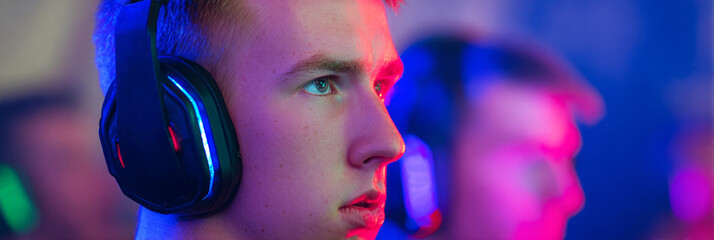 Fans eagerly watch from the stands as skilled gamers face off in a thrilling tournament, surrounded by dazzling lights and an energetic atmosphere that enhances the experience, banner