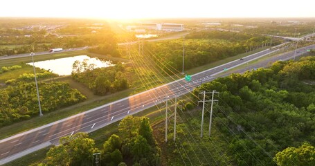 High voltage power lines on steel tower span across busy Florida highway with cars in motion. Electrical energy transmission over transportation route - Powered by Adobe