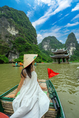 SIAN Woman tourist in boat on the river of the Tam Coc National Park Sightseeing tour to grottoes. Trang An, Ninh Binh, Vietnam.