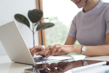Casual business woman online working on laptop with digital tablet on table, surfing the internet, online work, closeup. Woman hand typing on laptop computer keyboard on office table at home.