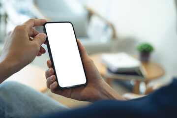 Cell phone blank white screen mockup. Woman hand holding, using mobile phone at coffee shop, empty space for social media marketing, mobile app design