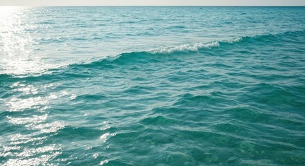 Obraz premium Sparkling turquoise ocean stretches towards a sunlit horizon, capturing ripples and small waves