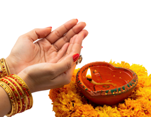 Lit clay lamp surrounded by flowers with hands in prayer gesture