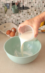 Anonymous person prepares dough with milk in bowl. Healthy eating with organic, gluten-free ingredients. Home cooking.