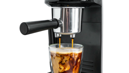 Espresso machine dispensing dark brew into a clear glass with creamy, swirling liquid