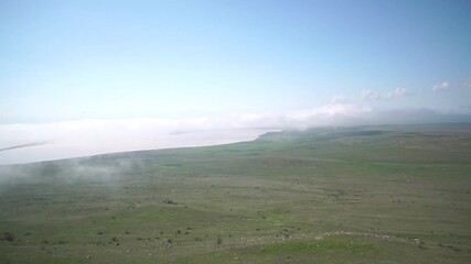 A foggy day with a lake in the background. The sky is clear and the sun is shining