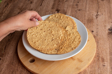 Manipulacion de alimentos, manejo de comida en la cocina, manos agarrando unas tostadas de maiz de un plato blanco sobre una mesa e la cocina