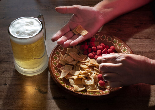 Manipulacion de alimentos, manejo de comida en la cocina, manos agarrando botanas o comida chatarra con un tarro de cerveza helada al lado