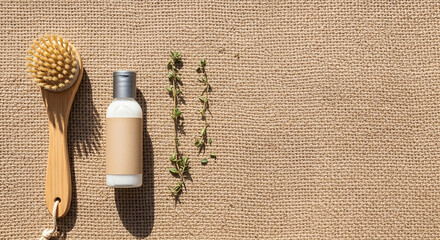 Natural Wooden Body Brush with Massage Head Bottle and Green Plant on Tan Textured Fabric Background