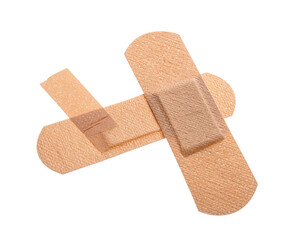 Two flesh-toned adhesive bandages arranged in a cross-like fashion, isolated on black