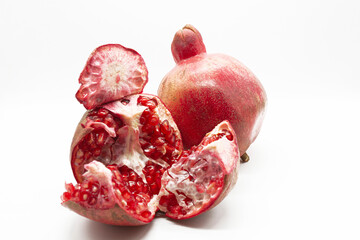 one open pomegranate and one whole pomegranate on a light, solid background