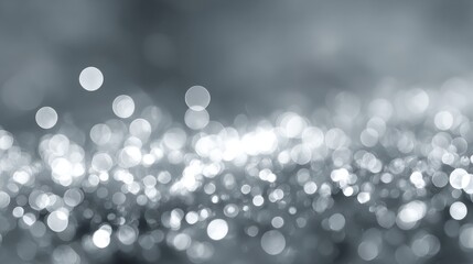 Abstract silver and white christmas bokeh lights with soft blurred glowing circles on a grey festive background for holiday designs and winter celebrations