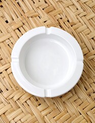 Empty white ashtray on woven surface
