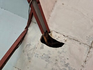 Damaged ceiling with visible hole and exposed wooden showing structural deterioration