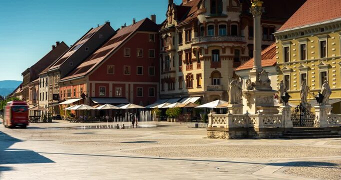 Maribor, Slovenia - August 9, 2025: A timelapse of Maribor&rsquo;s central square (Glavni trg), showing historic facades, the Plague Column, and people walking under bright summer sunlight.