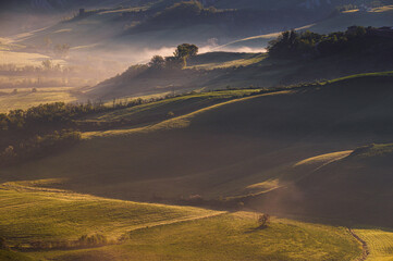 Obraz premium spring sunrise over the Tuscany hills with a farm house inside the valley, Italy