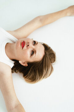 Portrait of a woman lying on a white surface looking at the camera