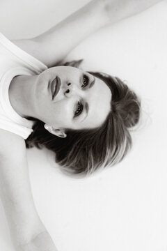 Portrait of a woman lying on a white surface looking at the camera
