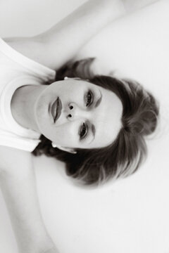 Portrait of a woman lying on a white surface looking at the camera