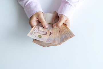 Money, Cash, Wealth, Hands holding a large amount of Thai baht banknotes, symbolizing cash, wealth, and financial success, close-up