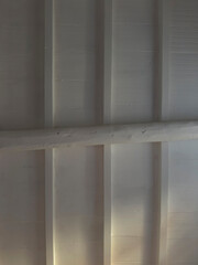 Wooden ceiling with exposed load-bearing beams, painted white, minimalist style