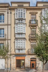 Fototapeta premium Traditional Spanish Building Facade with White Bay Windows and Iron Balconies