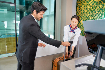 Scene of checking in at airport for businessman loading luggage with helping service of air ground at the airport.
