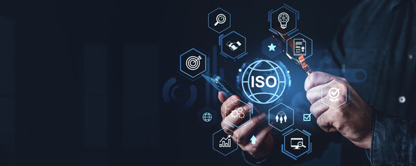 ISO quality certification concept with businessman analyzing standards and compliance through digital interface on dark background with high-tech icons.