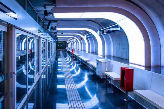 Hospitalet metro station platform, empty, modern and futuristic, with blue ambient lighting and protective doors for train access. Barcelona.