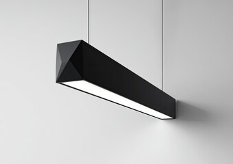 A modern, black, rectangular pendant light hangs from a white wall.  The light fixture's body is a matte black rectangle with angled facets.  A linear light source is visible within