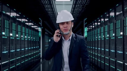 Front View of Asian Businessman Talking On Smartphone While Walking in Server Room Data Center - Powered by Adobe