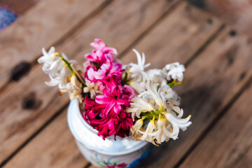 Colorful flowers in a white vase on a wooden table showcasing spring beauty