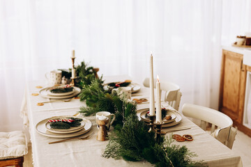 Elegant holiday dining setup featuring natural decor and candles in a bright room