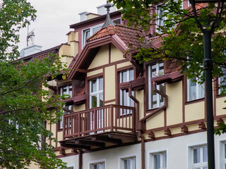 Historic half-timbered house with a decorative wooden balcony and flower boxes surrounded by summer greenery.