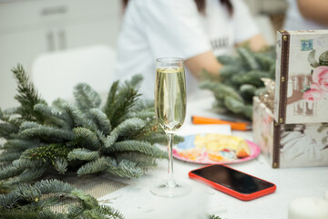 A master class on creating a Christmas or New Year's composition using spruce branches, a glass of champagne, and a smartphone