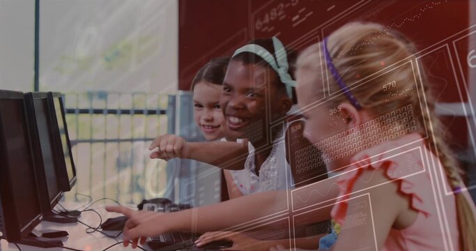 Pointing four girls leaning forward at monitors in school computer lab, with keyboards and mice