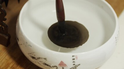 Students practicing calligraphy cleaning their brushes after live writing session in traditional ceramic bowl