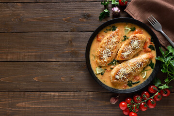 Chicken breast in creamy sauce with tomatoes and spinach on plate