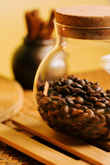 Glass jar filled with coffee beans on bamboo tray with aromatic spices nearby
