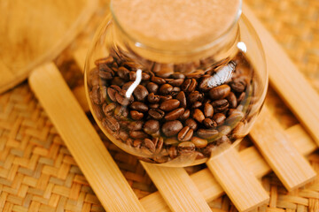 Glass jar filled with fresh coffee beans resting on a bamboo mat