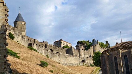 Carcassonne, France, features impressive medieval fortifications with stone walls and conical towers. The image showcases the city’s robust battlements, massive stone walls, and turreted towers  © Julija