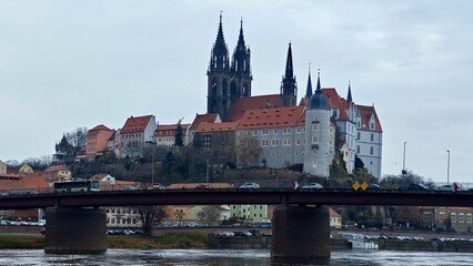 Fototapeta premium Panoramic view of Meissen, Germany features Albrechtsburg Castle and Meissen Cathedral atop a hill. The castle's Gothic architecture stands prominently with tall spires and intricate details. 