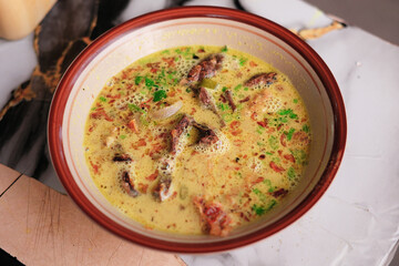 A top-down view of Soto Kuning Bogor, a traditional Indonesian yellow beef soup. The savory broth is garnished with a lime slice and fresh herbs, with a spoon resting in the bowl. Bogor popular Soup