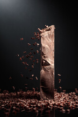 Large piece of dark chocolate and falling chocolate crumbs.