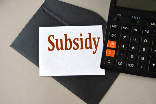 SUBSIDY - word on white sheet on black envelope with calculator