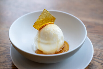 Honey ice cream with topping, served in a white bowl